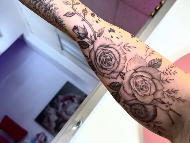 Fine line roses with a snail and leaves wrapping the forearm