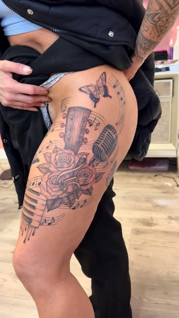 Guitar, microphone, butterfly and rose music tattoo on the hip and thigh