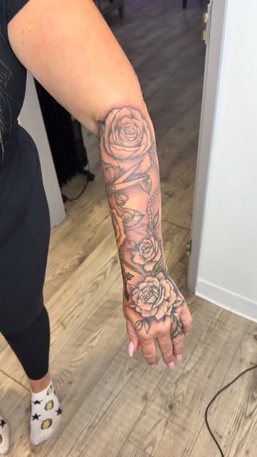 Black and grey roses with shading down the forearm and hand