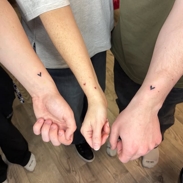 Tiny matching heart tattoos on three family members' wrists