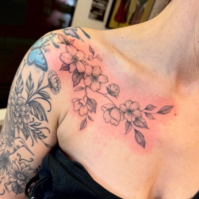 Fine line cherry blossoms along the collarbone and shoulder
