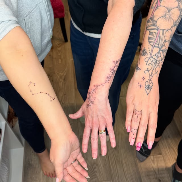 Three friends' matching fine line tattoos: constellation, vine and hand ornament