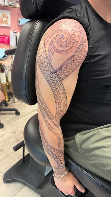 Polynesian-style linework sleeve over the shoulder and upper arm