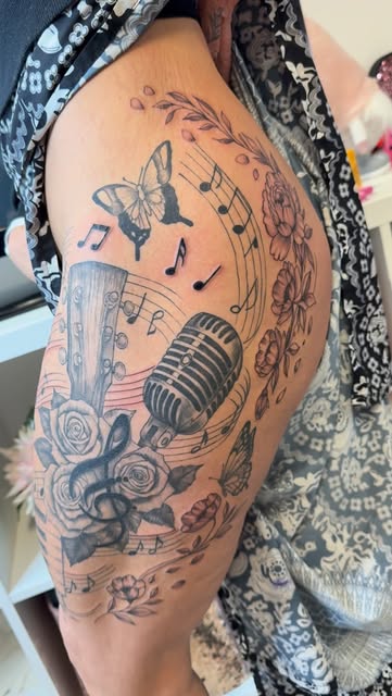 Music hip tattoo with guitar, microphone, roses and notes