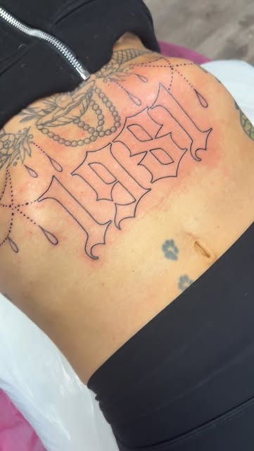 Blackletter "1981" with chain ornament on the lower back and hip