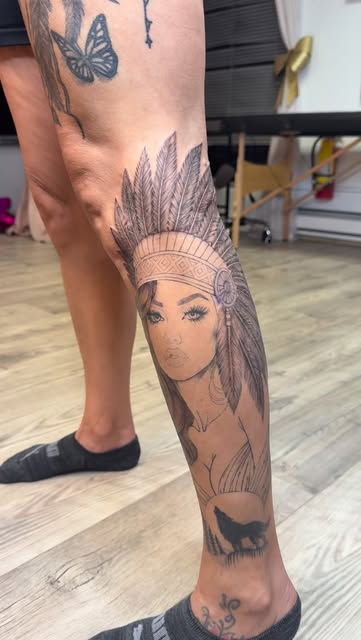 Black and grey portrait of a woman in a feather headdress on the calf