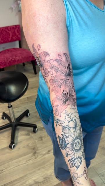 Lilies and sunflowers in a fine line floral sleeve down the forearm