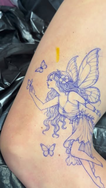 Blue stencil of a fairy with butterflies on the upper leg