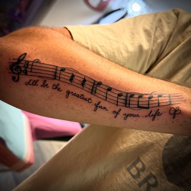 Music staff with handwritten lyric script along the forearm