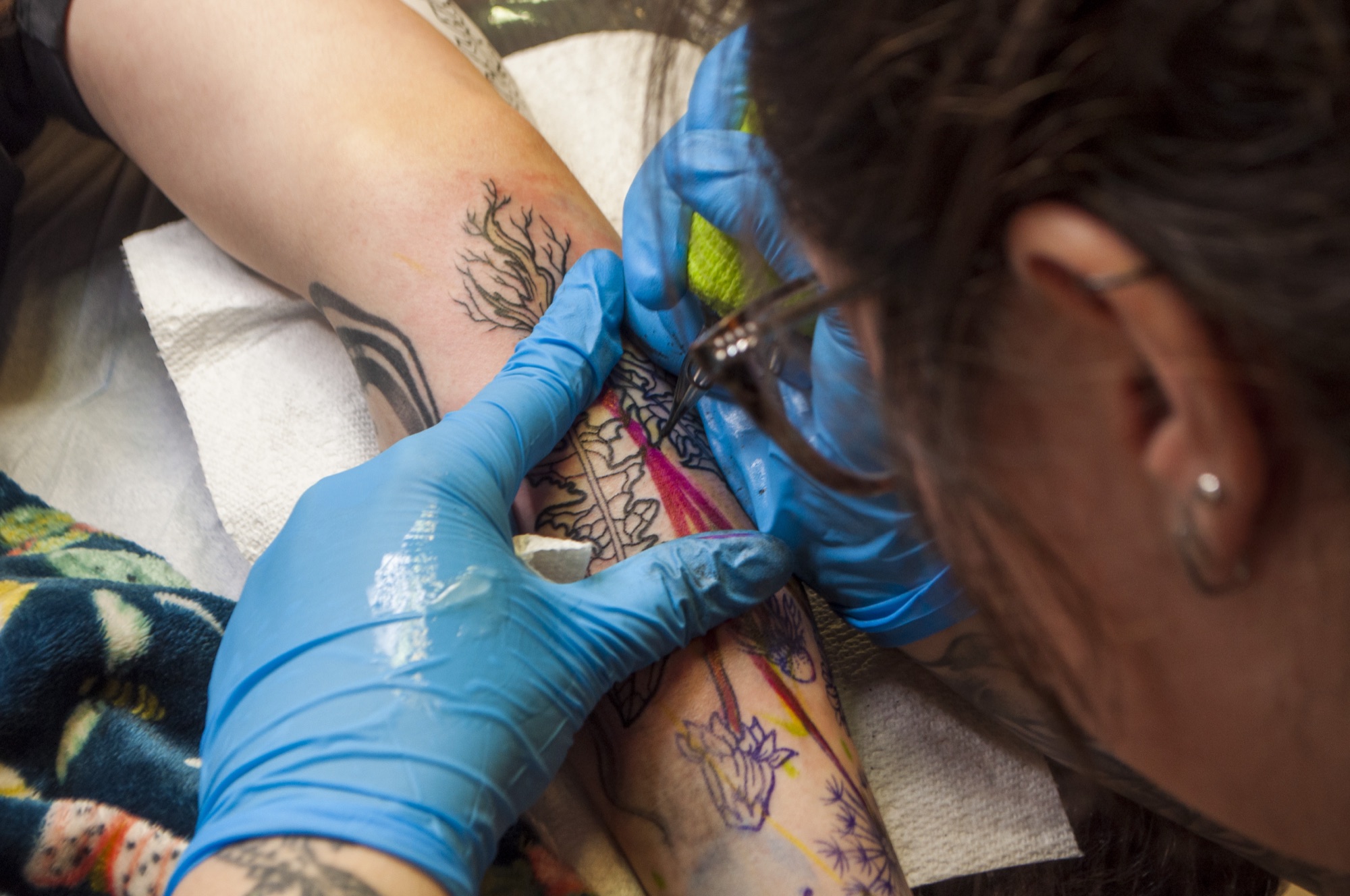 Close-up of Brynn tattooing botanical linework on an arm