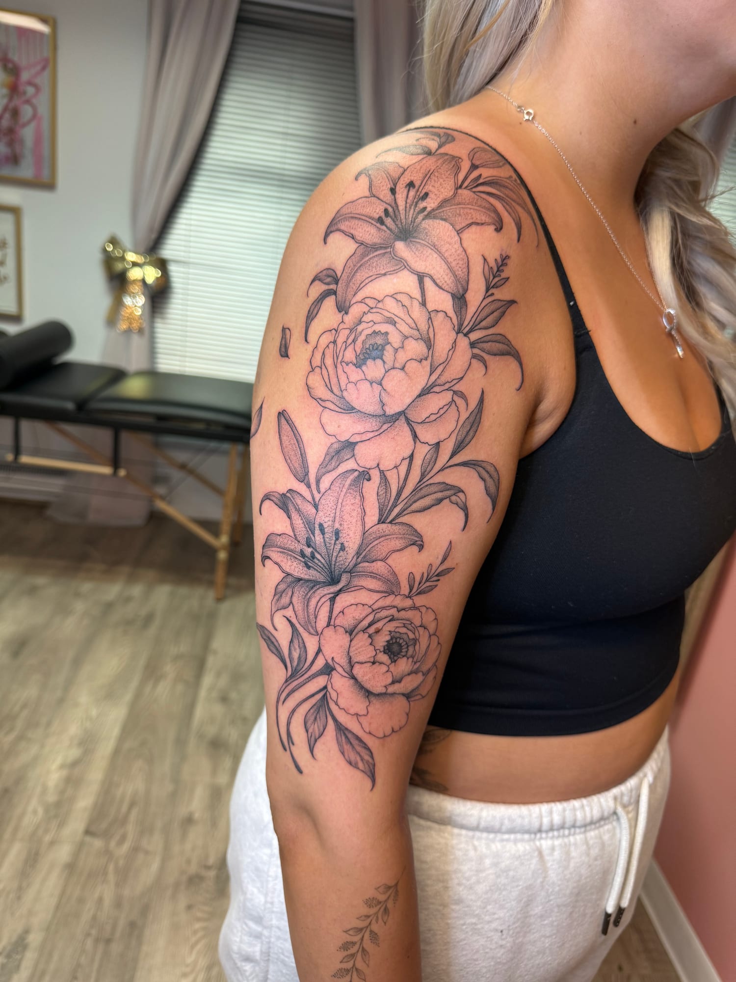 Fine line lilies and peonies flowing down the upper arm
