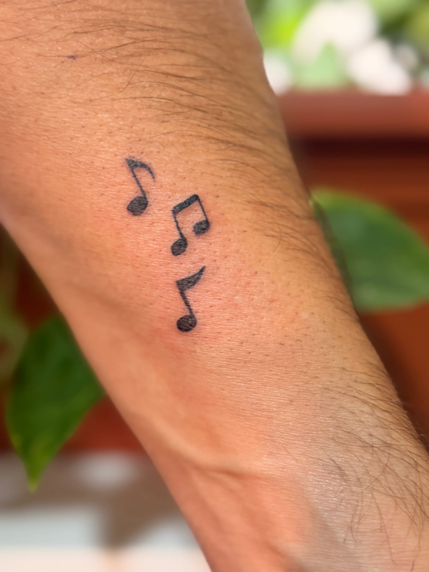 Three bold black music notes on the wrist